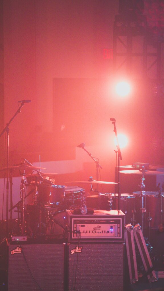 Ein Schlagzeug steht in rotem Bühnenlicht für einen Auftritt.